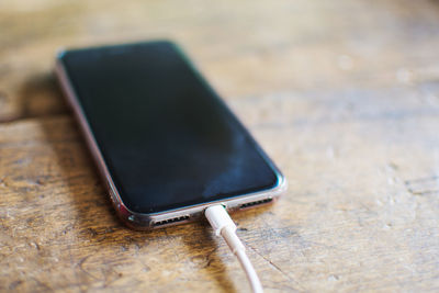 Close-up of phone getting charged on table