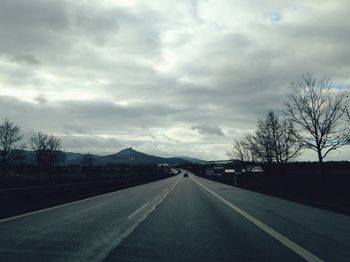 Empty road against cloudy sky