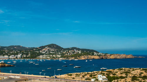 Scenic view of sea by city against blue sky