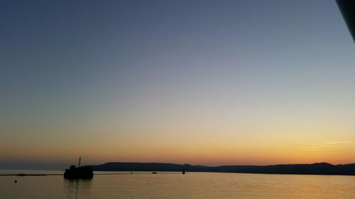 Boats in sea at sunset