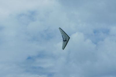 Low angle view of helicopter flying against cloudy sky