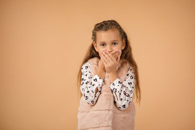 Young woman standing against yellow background