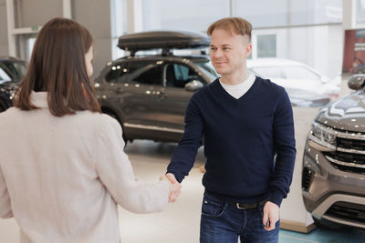 Side view of couple standing in car