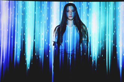 Close-up of woman standing against blue curtain