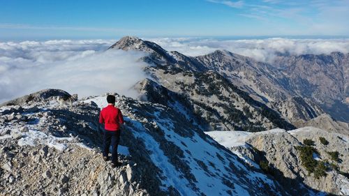 Rear view of person standing on snowcapped mountain against sky