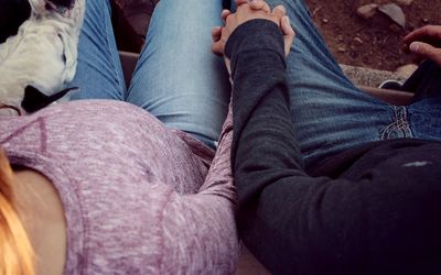 Midsection of man with pregnant woman sitting on bench