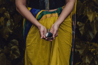 Midsection of woman holding umbrella standing in park