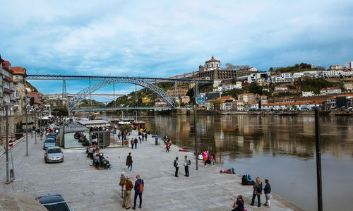 People on bridge in city against sky