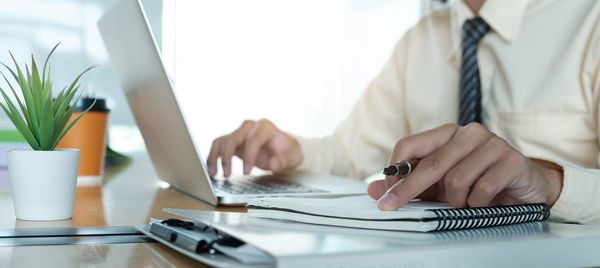 Midsection of man using laptop on table