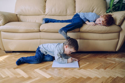 Rear view of boys relaxing on sofa at home