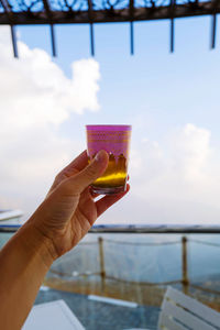 Hand holding moroccan tea in traditional tea cup against the clouds