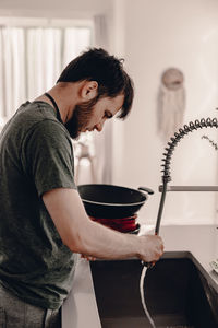 Side view of young man standing at home