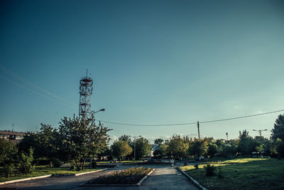 Road by trees against clear blue sky