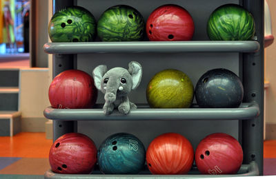 Close-up of stuffed elephant toy amidst colorful bowling balls in store