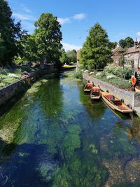 Punts moored in river against sky