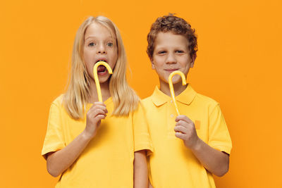 Portrait of boy playing with toy against yellow background