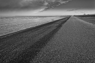 Tire tracks on beach against sky