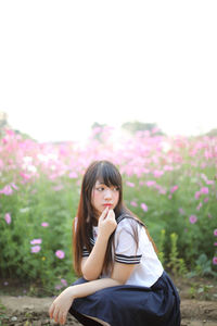 Beautiful woman crouching against flowering plants