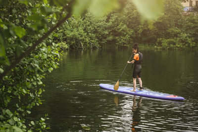 Full length of senior woman paddleboarding in sea during sup course