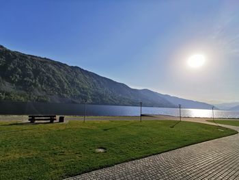 Scenic view of field by lake against sky