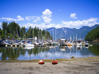 Sailboats moored in lake against sky