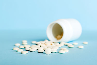 Pills spilling from bottle against blue background