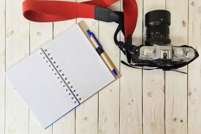 Directly above shot of camera and diary on wooden table