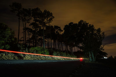 Light trails on road against sky at night