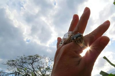 Low angle view of cropped hand against sky