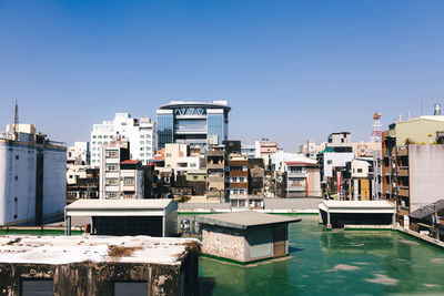 Buildings in city against clear blue sky