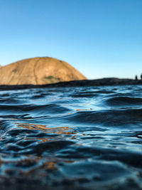 Surface level of sea against clear blue sky