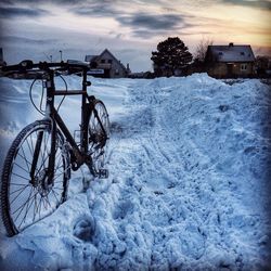 Snow covered field against cloudy sky