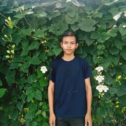 Portrait of young man standing against leaves