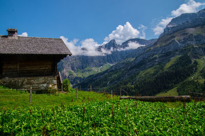 House on field by mountains against sky