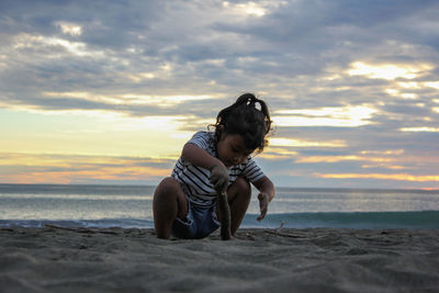 Full length of girl on beach against sky during sunset