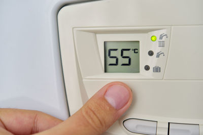 Cropped hand of person touching thermostat