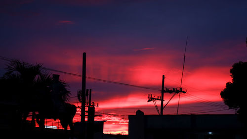 Low angle view of silhouette electricity pylon against sky during sunset