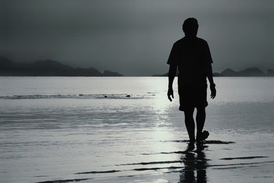 Rear view of silhouette man walking at beach