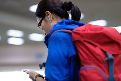 Side view of woman with backpack listening music