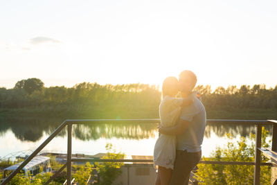 Couple standing by lake against sky