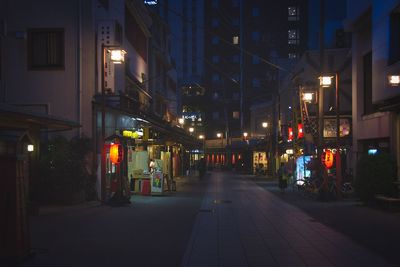 Illuminated street amidst buildings at night