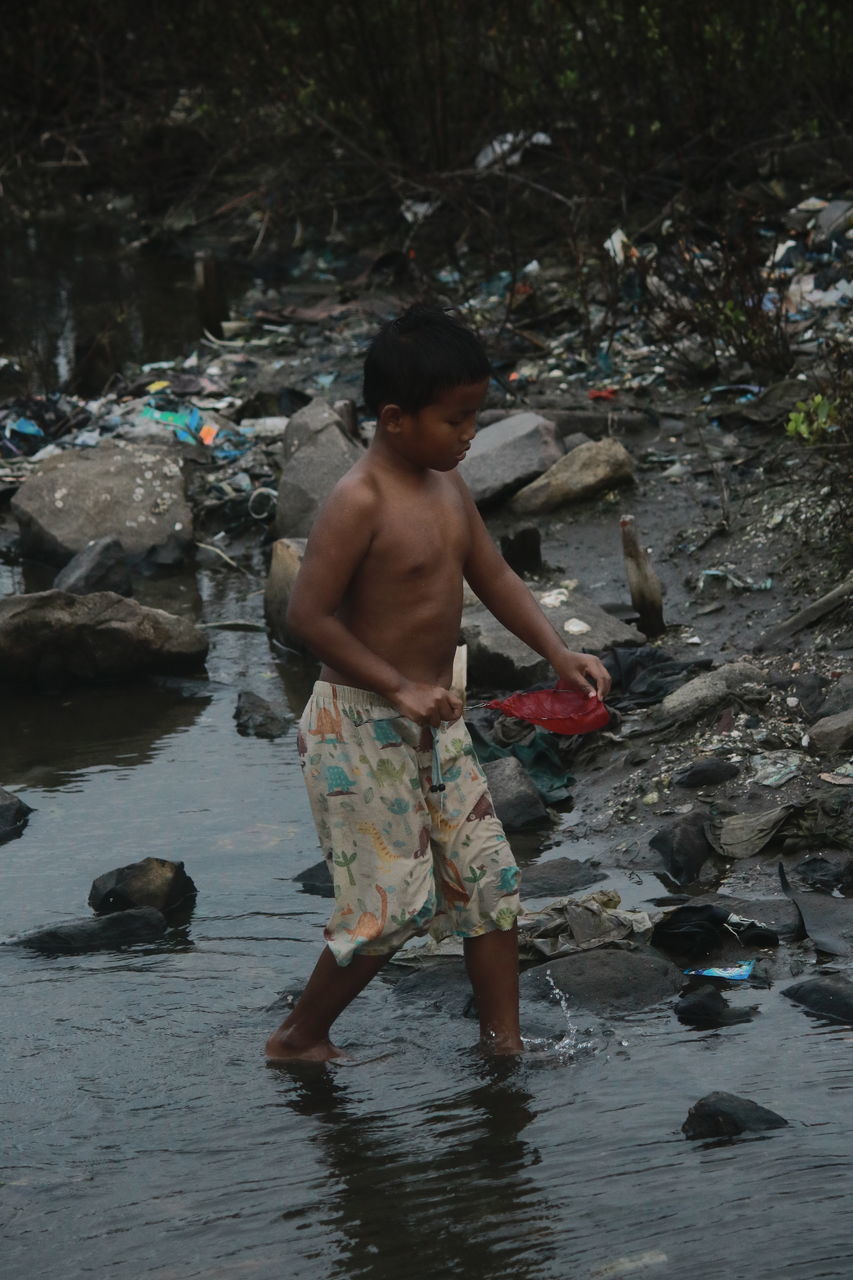 FULL LENGTH OF SHIRTLESS BOY STANDING IN WATER