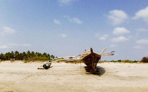 Fishing boat moored on seashore against sky