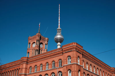 Low angle view of historic building and fernsehturm against clear blue sky