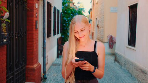 Young woman using mobile phone while standing on building