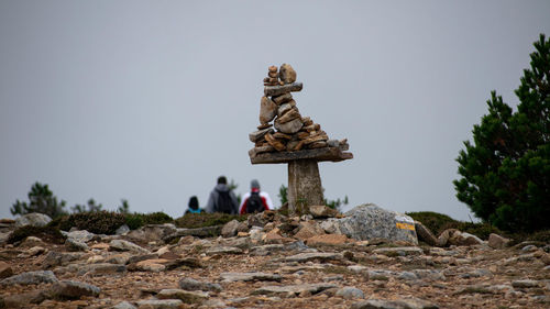 Group of people on rocks against clear sky