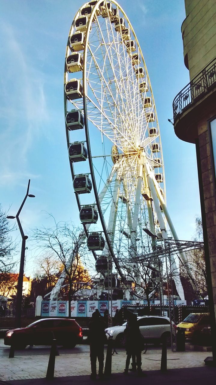 amusement park, ferris wheel, amusement park ride, arts culture and entertainment, built structure, architecture, sky, low angle view, leisure activity, tree, enjoyment, fun, building exterior, lifestyles, men, person, incidental people, large, large group of people