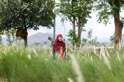 Woman standing on field against trees