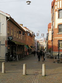 People walking on street in city against sky