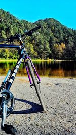 Bicycle by lake against clear sky